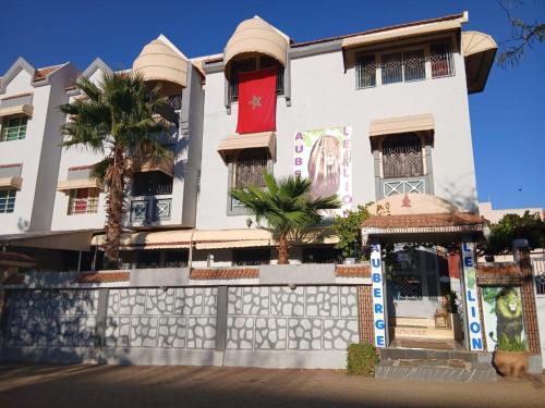 a white building with palm trees in front of it at Auberge Lion de l'Atlas in Azrou