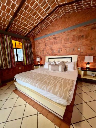 a bedroom with a large bed in a brick wall at Mama Chuy Hotel & Villas Ajijic in San Juan Cosalá