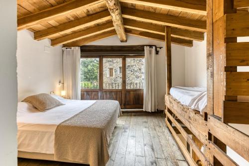 a bedroom with two beds and a large window at El Graner i El Niu in Sant Jaume de Llierca