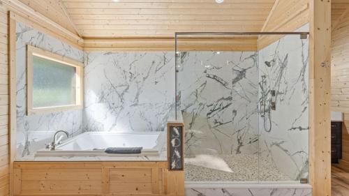 ein Badezimmer mit einer Badewanne und einer Marmorwand in der Unterkunft True Love Treehouse - Magic Above the Pines in Cleveland
