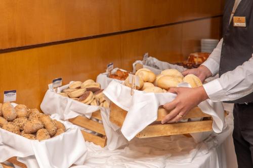 eine Person, die nach einem Tablett mit Brot greift in der Unterkunft VIP Executive Azores Hotel in Ponta Delgada