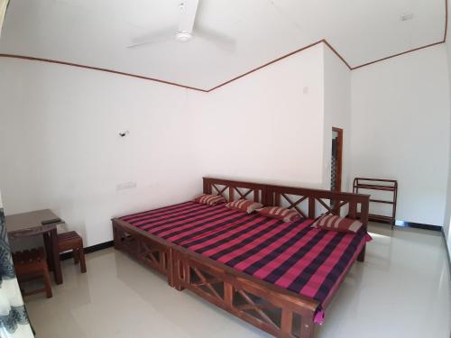 a bedroom with a wooden bed with a striped blanket at Adithya Resort in Nikawatawana