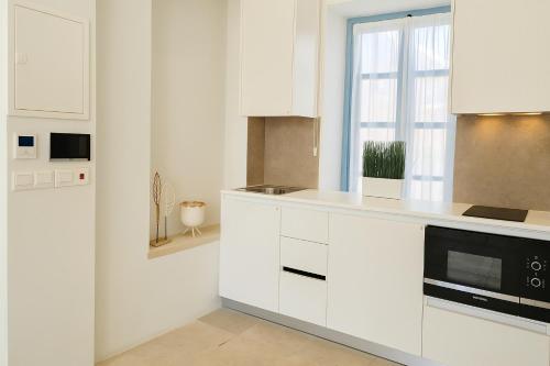 a white kitchen with white cabinets and a window at Central House in Limassol