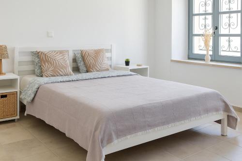 a white bedroom with a large bed with pillows at Central House in Limassol