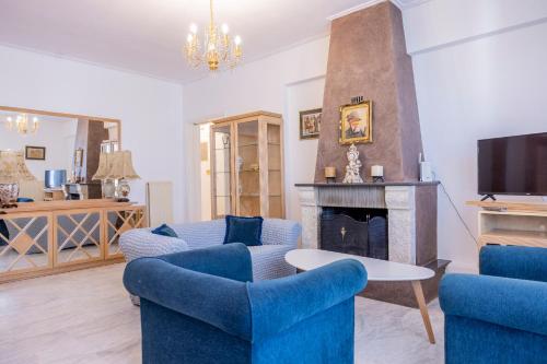 een woonkamer met blauwe stoelen en een open haard bij Trikala Homey Vibes in Tríkala
