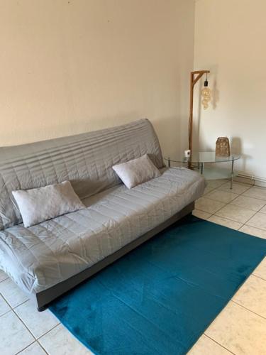 een bank in een kamer met een blauw kleed bij A l'orée des bois in Lyons-la-Forêt