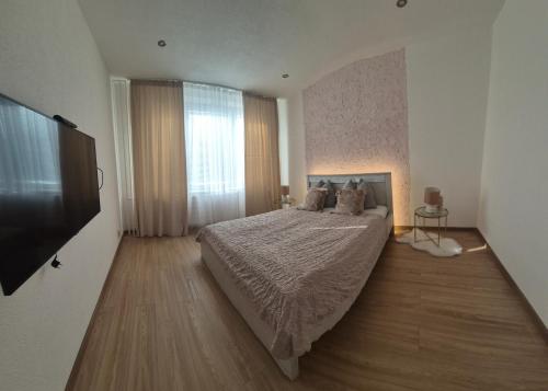 a bedroom with a bed and a flat screen tv at Apartmán LUX Lučenec in Lučenec