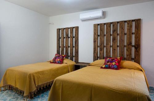a bedroom with two beds with yellow sheets and a window at Hotel Cassaterra in Ciudad Valles