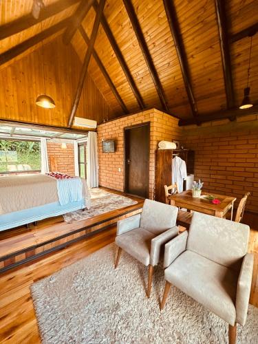 a bedroom with a bed and two chairs and a table at Maria Rita dos Canyons in Praia Grande