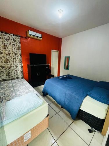 a bedroom with two beds and a television in it at Hotel Guanabara Cuiaba in Cuiabá