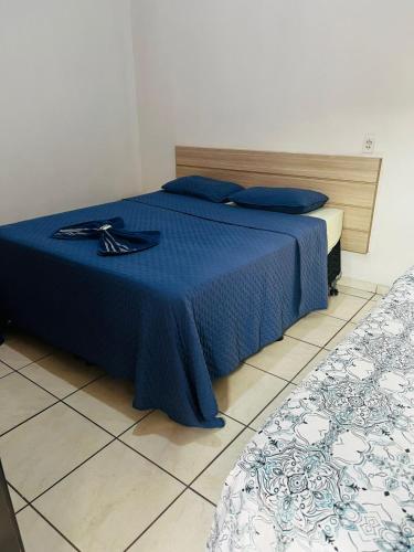 a bedroom with a bed with a blue comforter at Hotel Guanabara Cuiaba in Cuiabá