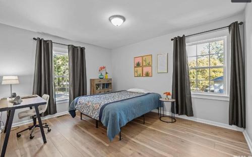 une chambre avec un lit, un bureau et des fenêtres dans l'établissement Stylish 4BR Getaway with Game Room, Grills & Cozy Outdoor Fire-Pit, à Cary