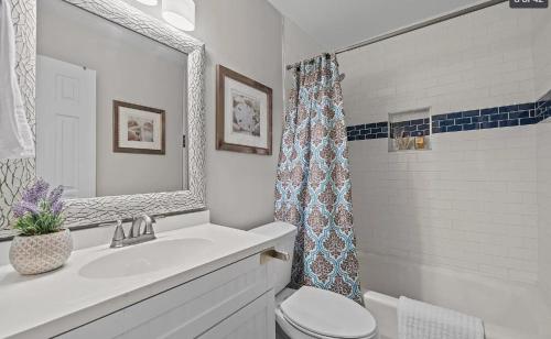 une salle de bain avec un lavabo, des toilettes et un miroir dans l'établissement Stylish 4BR Getaway with Game Room, Grills & Cozy Outdoor Fire-Pit, à Cary