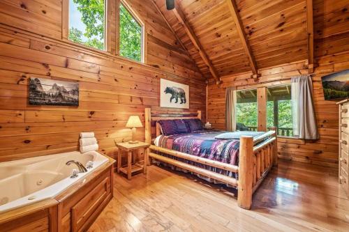 a bedroom with a bed and a tub in a log cabin at Luxury Cabin • 4 King Beds • Jacuzzi in Each Room in Cartertown