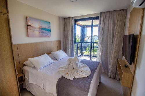 une chambre d'hôtel avec un ours en peluche assis sur un lit dans l'établissement Cais Eco Residência, Luxo, Requinte e Conforto em Muro Alto, à Porto de Galinhas