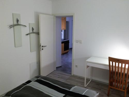 Dieses weiße Zimmer verfügt über einen Schreibtisch und einen Tisch. in der Unterkunft Ferienwohnung Blissenbach in Kürten