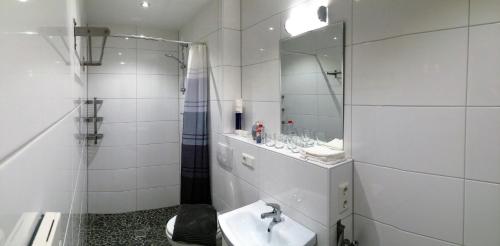 ein weißes Badezimmer mit einem Waschbecken und einem Spiegel in der Unterkunft Ferienwohnung Blissenbach in Kürten