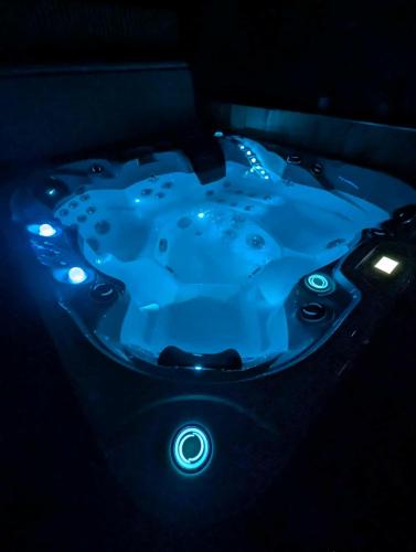 - un bain à remous bleu éclairé dans une pièce sombre dans l'établissement Gite de campagne avec SPA privatif, à Saint-Sauvant