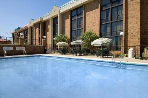a pool in front of a hotel with tables and umbrellas at Hotel Lotus Kansas City Stadium in Kansas City