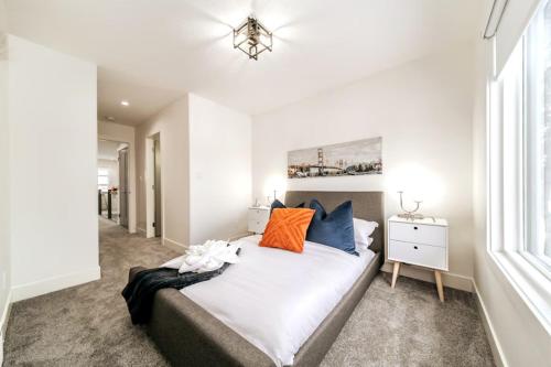 a bedroom with a bed with orange and blue pillows at 5BDRM Chic Modern Home-Hot Tub-King Bed-AC-Garage in Edmonton