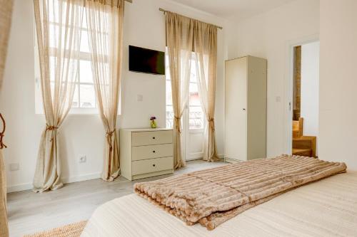 a bedroom with a bed and a dresser and windows at Elegant City House Moderno no Centro da Cidade in Chaves