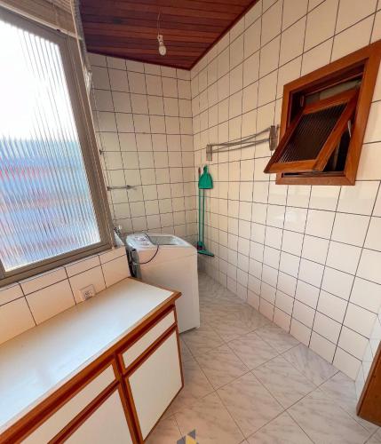 a tiled bathroom with a sink and a toilet at Apartamento frente mar com 3 quartos in Torres
