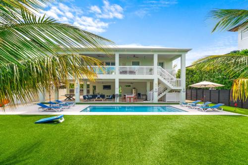 a villa with a swimming pool and a house at Emerald Oasis Deluxe Waterfront Gem, Heated Pool with Dock in Marathon