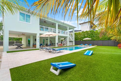 a villa with a swimming pool and a house at Emerald Oasis Deluxe Waterfront Gem, Heated Pool with Dock in Marathon