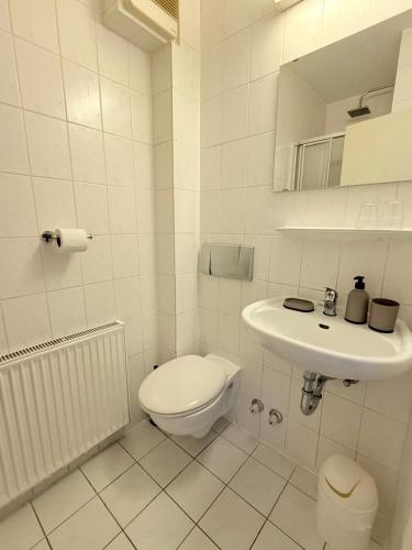 a white bathroom with a toilet and a sink at Hotel & Pension Bockenem in Bockenem