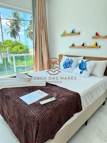 a bedroom with a large bed with a sign that reads akuna class mares at Pousada Tábua das Marés in Japaratinga