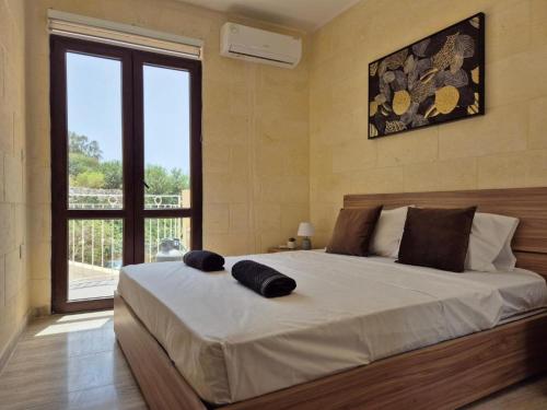 a bedroom with a large bed with a large window at Dar il-Wied in Għajn il-Kbira