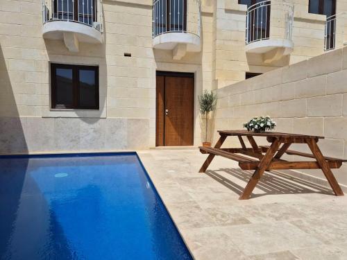 a wooden picnic table next to a blue pool at Dar il-Wied in Għajn il-Kbira