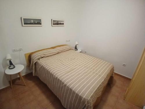 a bedroom with a bed and a table and two pictures on the wall at Luz del Guadiana in Ayamonte