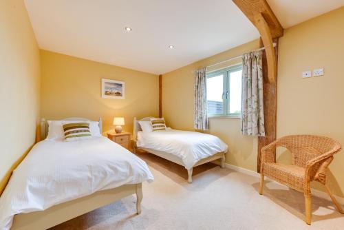 two beds in a room with a chair and a window at Pheasant Lodge in Reepham
