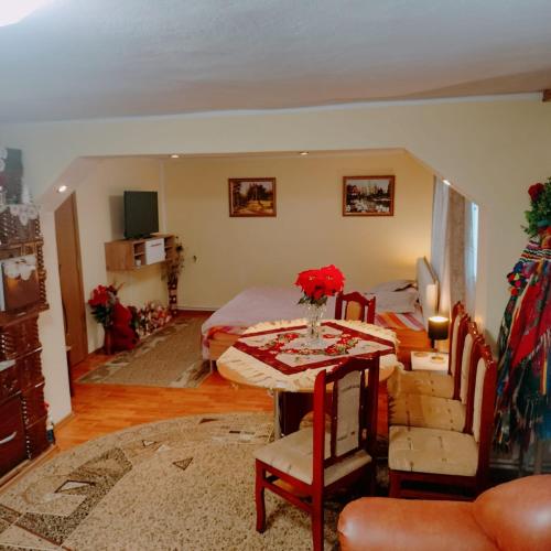 a living room with a bed and a table with flowers on it at Casa Tudor-Nicolae in Borşa