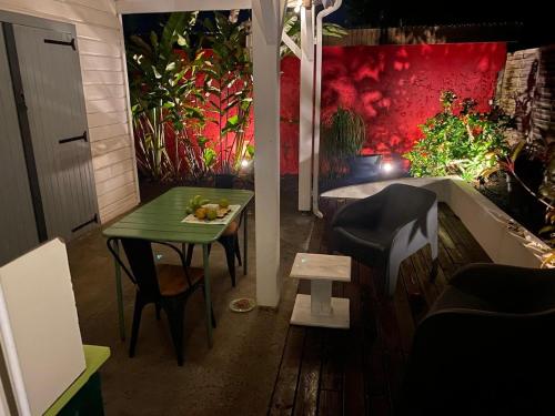 Habitación con mesa, mesa verde y sillas. en Lukila Bungalow At Rustine and Pompette's, en Saint-François