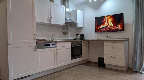 een keuken met witte kasten en een vuur aan de muur bij FEWO VRONI - Wohlfühlambiente mit Stil und Terasse in Rattelsdorf