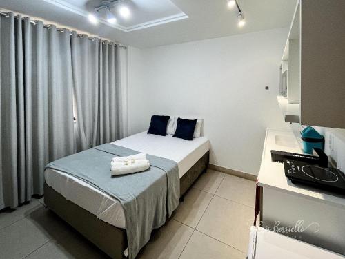 a small bedroom with a bed with blue pillows at Studio Novíssimo Mauá 1108 in Rio de Janeiro