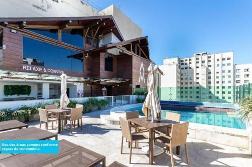 a patio with tables and chairs next to a pool at Studio Novíssimo Mauá 1108 in Rio de Janeiro