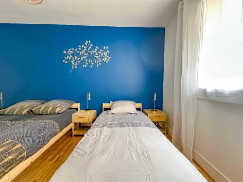zwei Betten in einem Zimmer mit einer blauen Wand in der Unterkunft L'aube Climatisation Parking 2 chambres in Grenoble