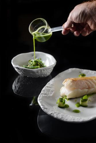 a person is pouring sauce on a plate of food at Le Kaïla in Méribel