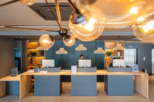 a man sitting at a desk in an office with lights at Ibis Florianopolis in Florianópolis
