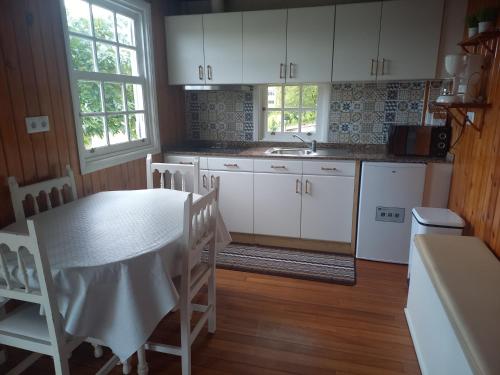 セデイラにあるLa cabañaの白いキャビネットとテーブルと椅子のあるキッチン