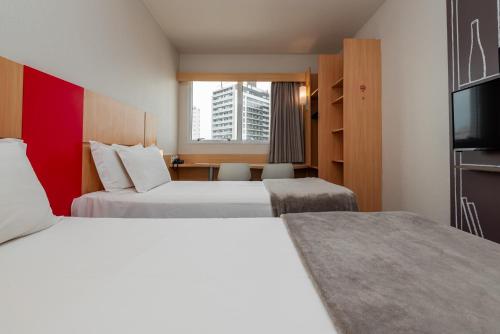 Una habitación de hotel con dos camas y un televisor. en Ibis Florianopolis, en Florianópolis