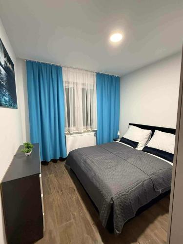 a bedroom with a large bed and blue curtains at Apartament Zefir in Busko-Zdrój