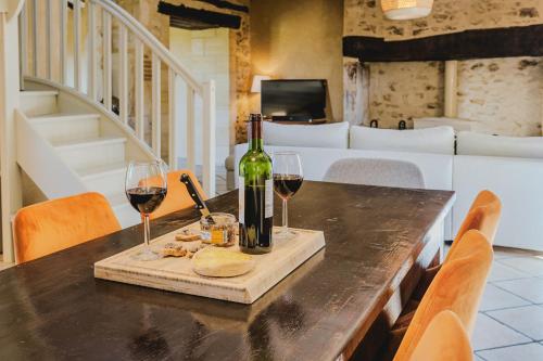 a table with a bottle of wine and two glasses at Le Logis de Saint-Chamassy in Saint-Chamassy