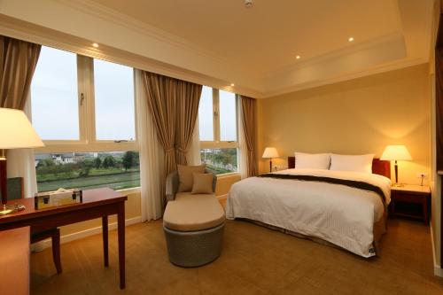 a hotel room with a bed and a desk and window at Aleex Villa in Yuanshan