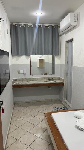 a bathroom with a large mirror and a sink at Hotel Angely in Belo Horizonte