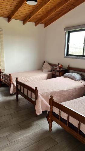 une chambre avec trois lits et une fenêtre dans l'établissement Hostal patronal bypass el rosal k485, à Salto del Laja