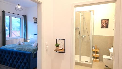 a bedroom with a blue bed and a bathroom at Black Forest -5- I Design-Apartment I 2 Etagen I Terrasse & Balkon mit Ausblick I Boxspring I Nespresso in Oberharmersbach